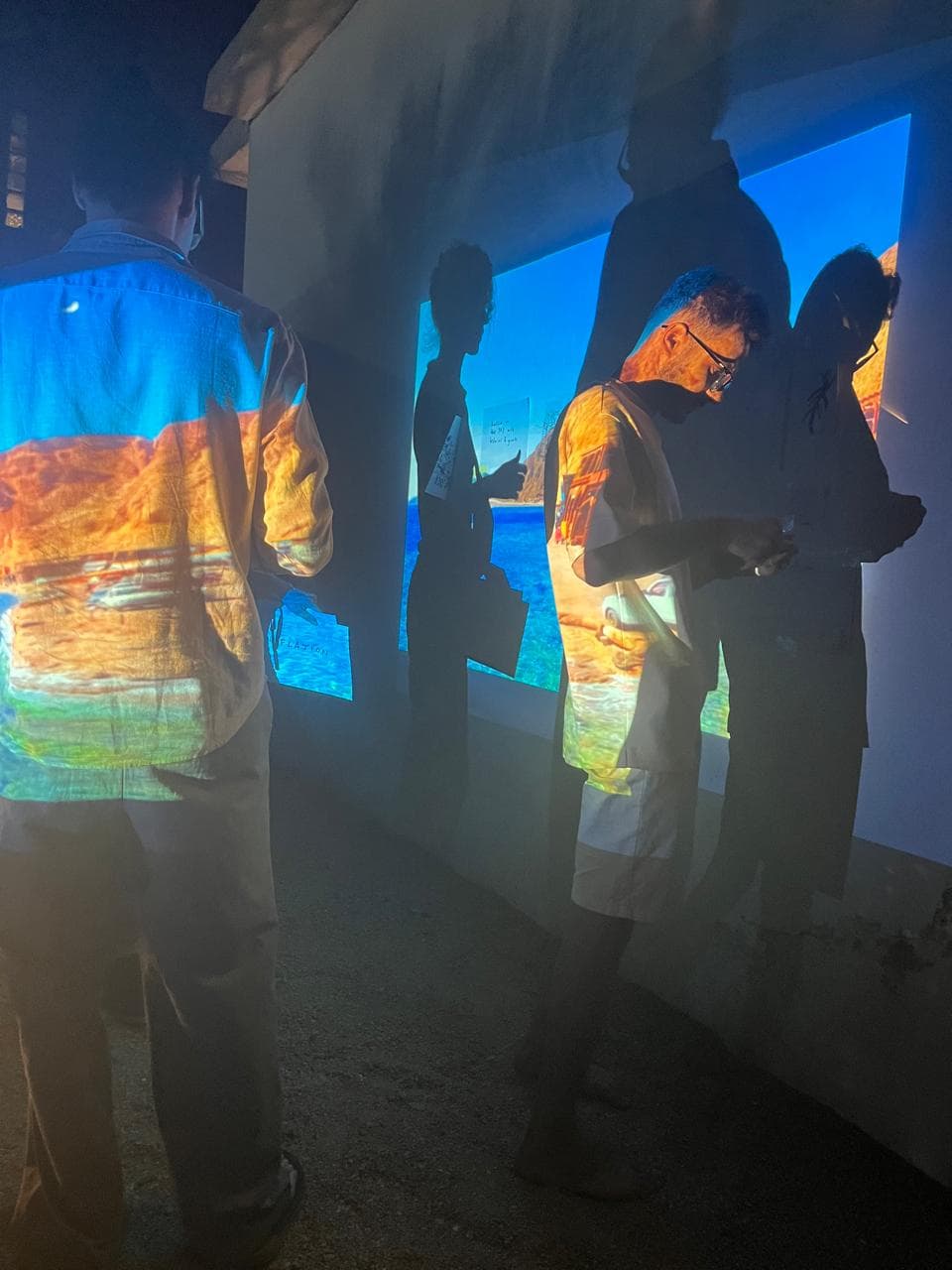 Visitors walking through a projected Dahab seascape during an art projection at SA Studios